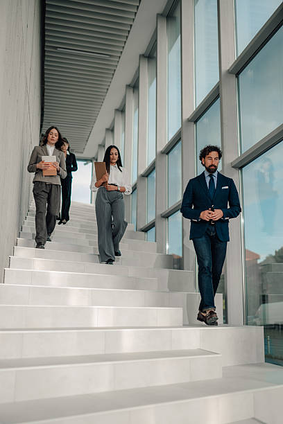 istock Businesspeople walking down stairs in modern office building 2225451457