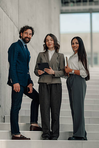 istock Business team smiling at camera while standing on stairs 2225451471