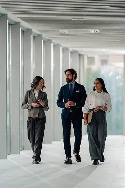 istock Businesspeople walking and talking in modern office hallway 2225451494
