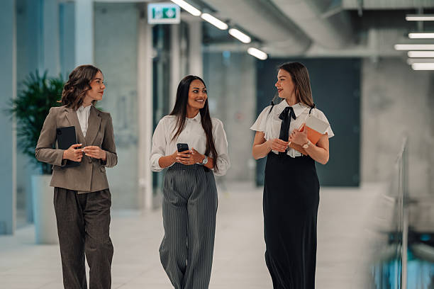 istock Businesswomen walking and talking in modern office hallway 2225451502