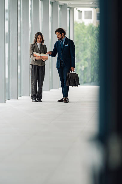 istock Businesspeople discussing book in modern office hallway 2225451587