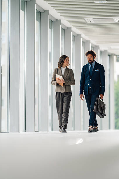 istock Businesspeople walking and talking in modern office hallway 2225451596