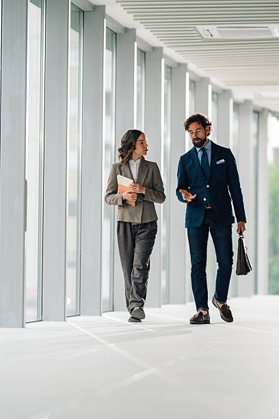 istock Businesspeople walking and talking in modern office hallway 2225451597