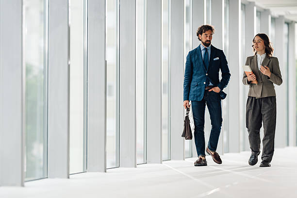 istock Businesspeople walking and talking in modern office hallway 2225451604