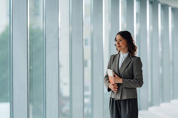 istock Businesswoman holding notebook looking out office window contemplating future plans 2225451609