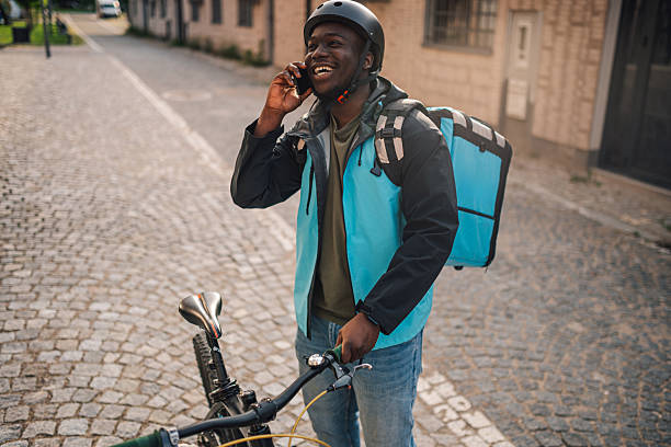 istock Delivery man talking on the phone while holding his bicycle 2225454687