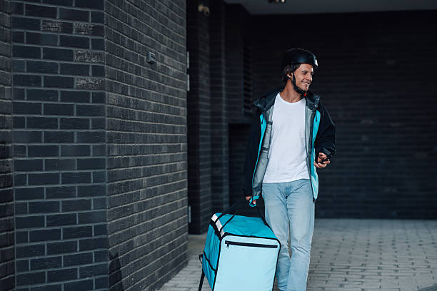 istock Delivery man carrying thermal backpack walking near building 2225454750