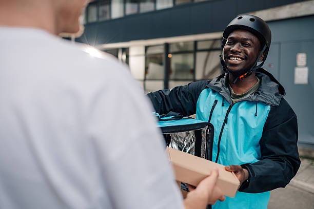 istock Smiling delivery man delivering food to a customer 2225454882