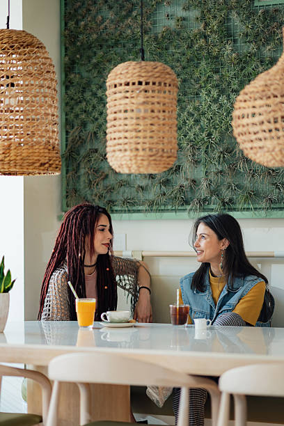 istock Two young women talking and drinking beverages at a trendy cafe 2225456178