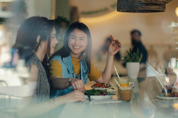 istock Two young women having lunch together at a restaurant window table 2225456270