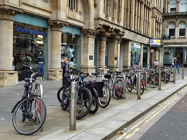 Glasgow, Scotland, UK - July 29, 2024: Bicycle parking station at Nelson Mandela Place in Glasgow. People walking along the buildings. At the background old stone buildings