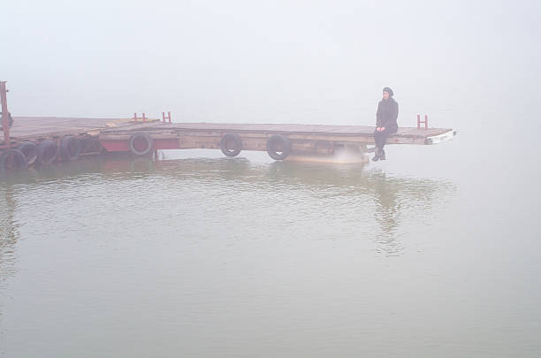 istock Young woman sitting on the river dock in autumn 2225458213