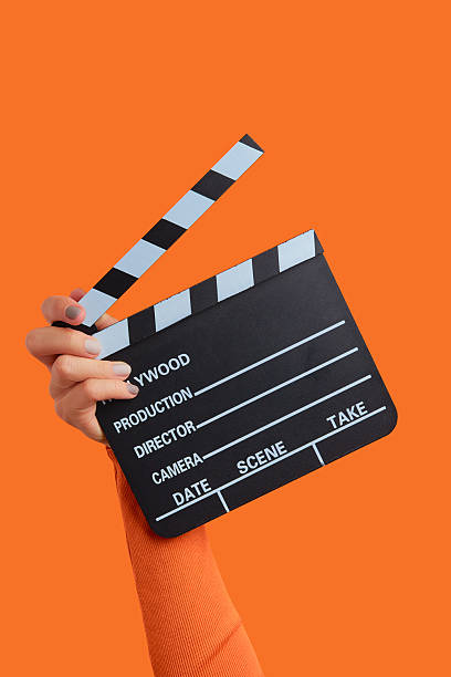 istock Womans hand holding clapperboard on an orange background 2225465970