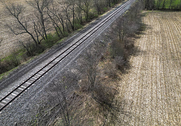 Railroad tracks through a cornfield as seen from a drone in Columbus, Pennsylvania, USA on a sunny spring day