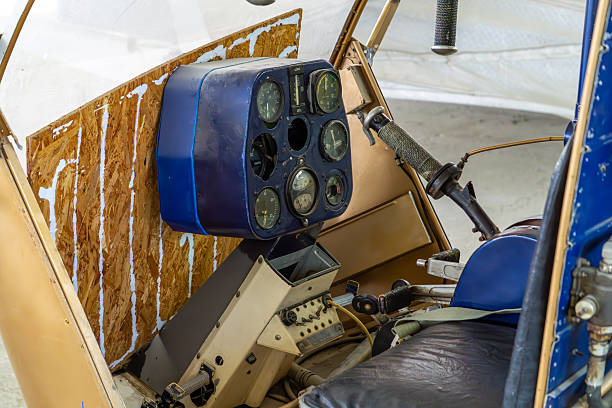 Interior of an old helicopter with instrument panel and control stick, inside an abandoned hangar.