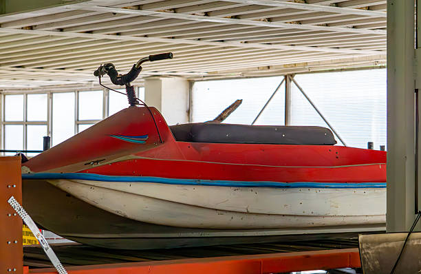 istock Red and white jet ski with handlebar, placed on a metal platform inside a hall. 2225495354