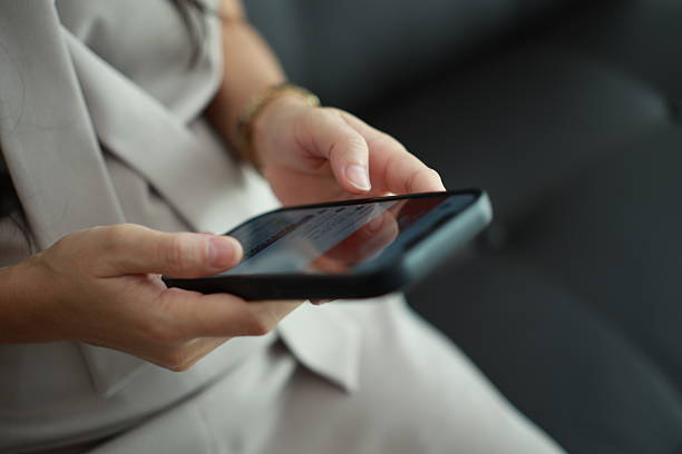 istock Using phone, closeup of a hand holding smartphone on sofa 2225496872