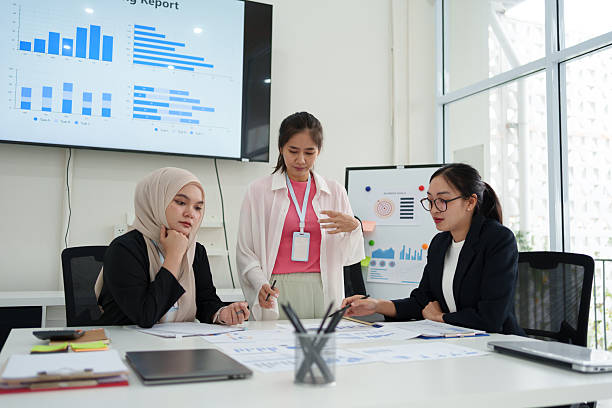 istock Group of diverse businesswomen collaborating on project in modern office, analyzing charts and data with focus. 2225498198