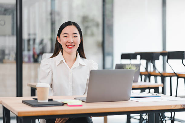 istock Confident businesswoman smiling while working on laptop in modern office setting. 2225498343