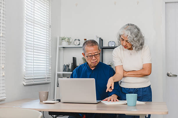 istock Elderly couple working together on laptop and documents at home, showing focus and collaboration in bright room 2225499123