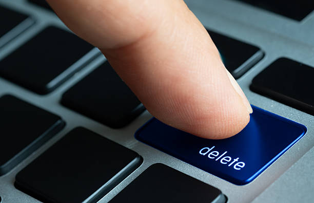 Finger of the computer user, he presses the delete button on the computer keyboard.