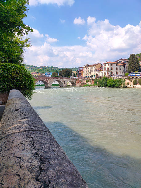 Verona, Italy - May 12, 2025: River view with bridge and Castelvecchio castle, a Middle Ages red brick castle on the right bank of River Adige, Verona, Veneto, Italy, Europe