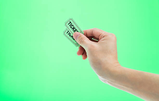 istock Hand holding two cinema tickets on green background 2225510287
