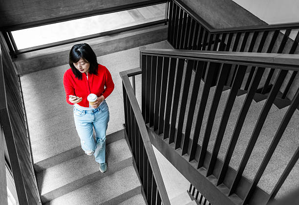 istock Woman texting and drinking coffee as she walking down the stairs 2225510384