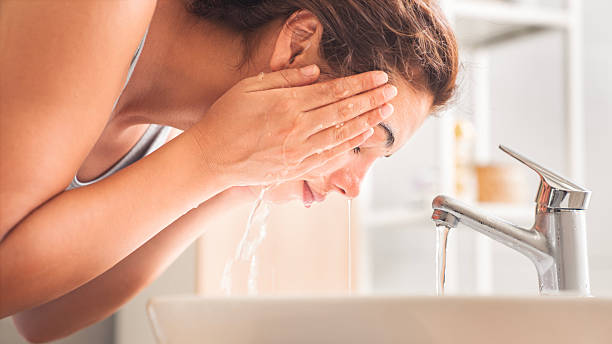 istock Young woman washing her face in bathroom 2225514334