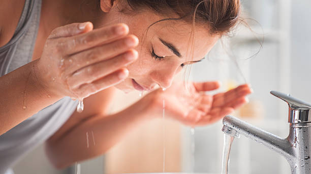 istock Young woman washing her face in bathroom 2225514421