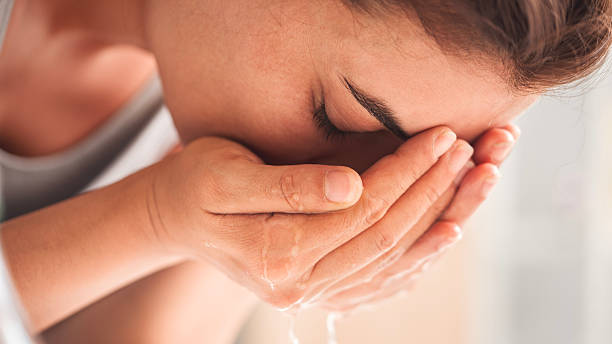 istock Young woman washing her face in bathroom 2225514446