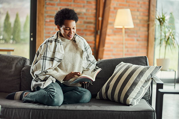 istock Happy black woman reading a book at home. 2225514664