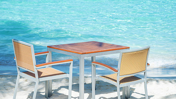 Empty table and chairs on tropical beach by beautiful turquoise sea