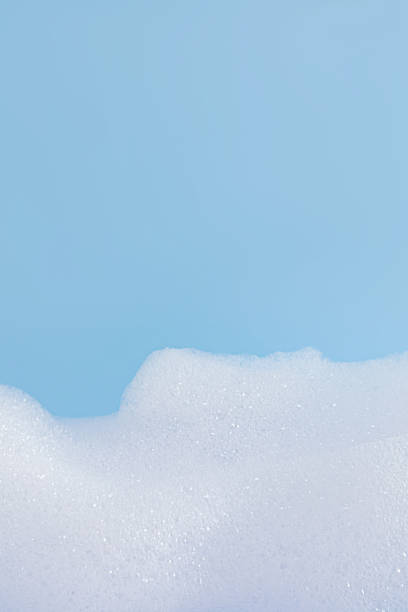 istock Texture of white bubble bath, soap, laundry detergent on a blue background. Layout for the presentation of your cosmetic product. Vertical view. 2225516250