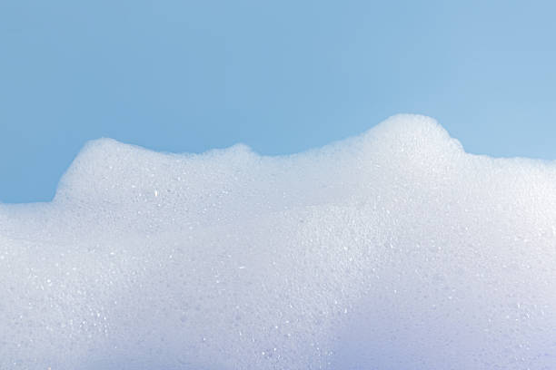 istock Texture of white bubble bath, soap, laundry detergent on a blue background. Layout for the presentation of your cosmetic product 2225517556