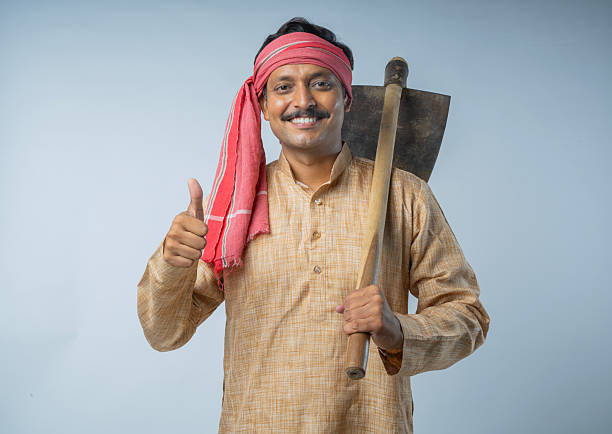 Portrait of happy mid adult farmer holding hoe and gesturing while standing on white background