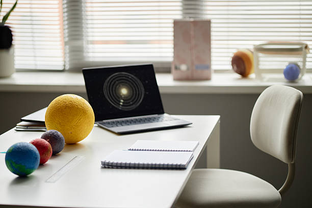 istock Solar System Model Displayed on Desk with Laptop Showing Planetary Orbits 2225526168