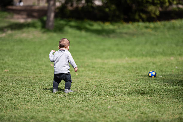 istock Baby walking on grass towards ball in park 2225529192