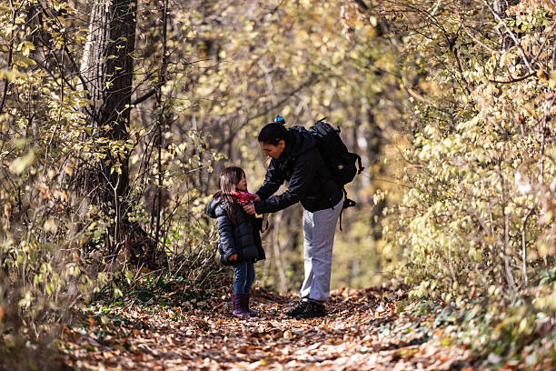 Mother and daughter sharing joyful moments while hiking through the vibrant woods on a stunning autumn day filled with colorful leaves