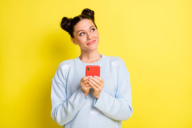 istock Photo of lady hold smartphone look up empty space think wear blue pullover isolated yellow background 2225534401