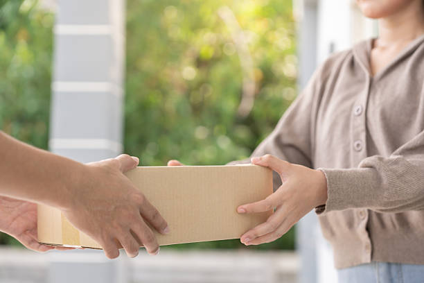 istock woman receives boxes parcel from courier in front house. Delivery man send deliver express. online shopping, paper containers, takeaway, postman, delivery service, packages 2225537882