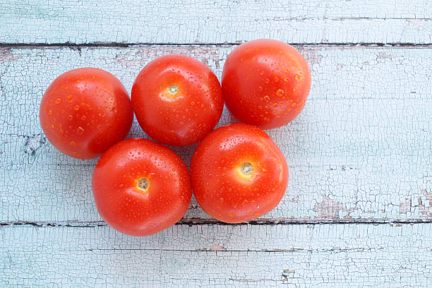 istock Fresh tomatoes with water droplets on rustic wooden background. 2225538597