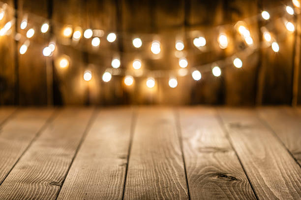 Empty rustic wooden table with blurred Christmas lights at background. Copy space. Illuminated party background