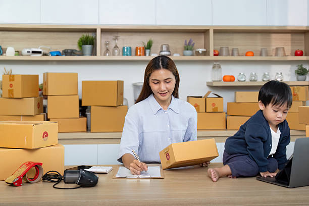 istock Sell Online: A mother organizing her e-commerce business with her child beside her 2225539207