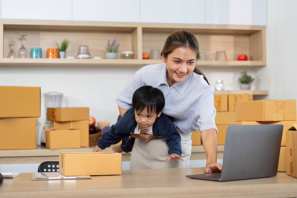istock Sell Online: A mother managing her e-commerce business while caring for her child 2225539312