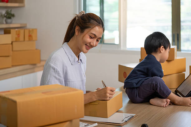istock Sell Online: Smiling mother labeling packages in home workspace 2225539412