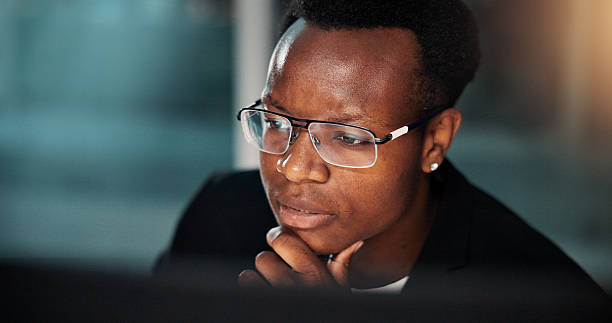 istock Night, black man and employee with computer, thinking and ideas for reading and online solution. Person, evening and consultant with technology, problem solving or planning with internet or project 2225547577