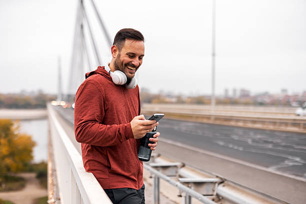 istock Smiling Man Enjoying Outdoor Activity on a Bridge While Using Smartphone 2225549038
