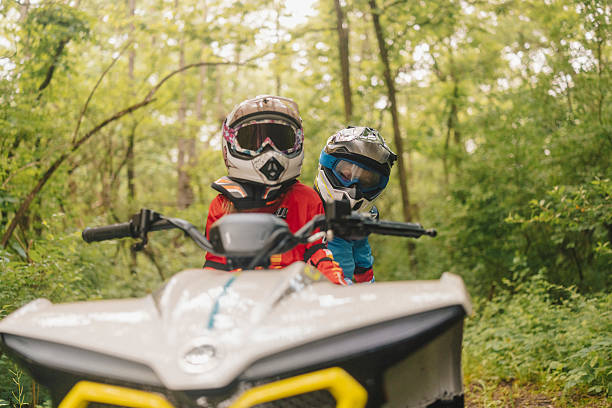 istock Two young siblings enjoy an exciting ride on a children’s ATV, surrounded by a green forest. The older sister confidently drives while her younger brother holds on behind her 2225549826