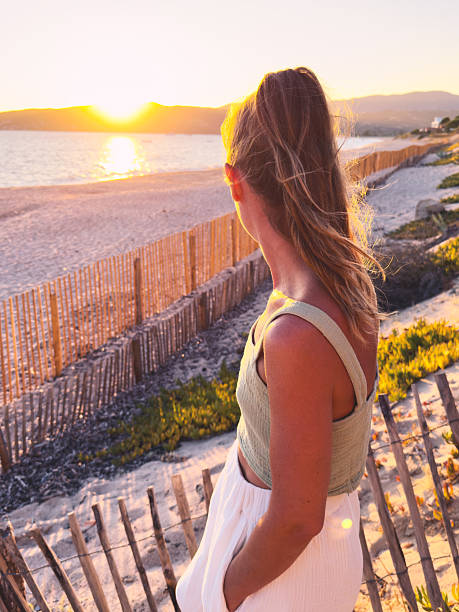 istock Woman Watching Sunset Over Sandy Beach 2225551327